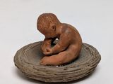 a small figurine of a boy sitting on top of a nest
