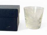 un verre d'eau posé à côté d'une boîte sur une surface blanche