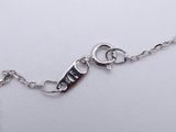 a silver bracelet with a key on it on a white surface