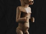 une statue en bois représentant un homme avec une cigarette à la bouche