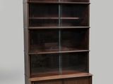 une bibliothèque en bois avec des portes vitrées et des étagères, sur fond gris