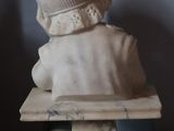 a marble bust of a child sitting on a bench