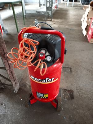 a red air compressor sitting on a cart in a warehouse