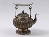 une théière ancienne en argent, munie d'une anse et posée sur un socle