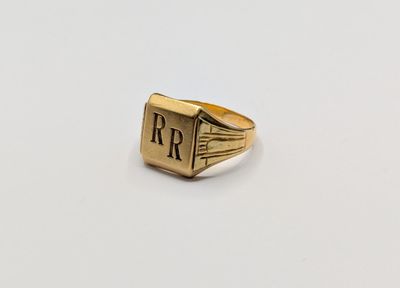un gros plan d'une bague en or sur laquelle figure la lettre « r »