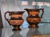 two vases sitting on a glass table in front of a window