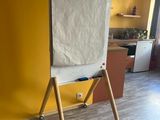 un tableau blanc posé sur un support en bois dans une pièce jaune