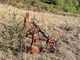 a rusted plow sitting in the middle of a field