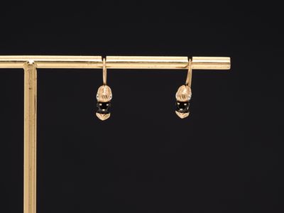 a pair of black and gold earrings on a wooden stand