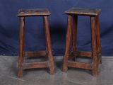 une paire de tabourets anciens en bois avec des assises en cuir, sur fond bleu