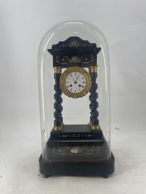 a small clock under a glass dome on a table