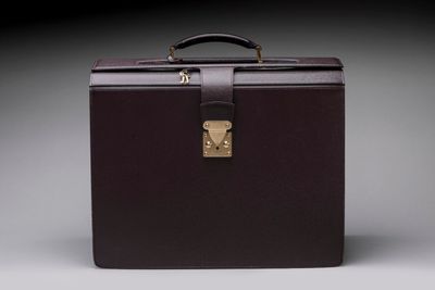brown leather briefcase with brass lock and handle on grey background