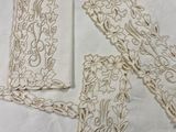 three pieces of embroidery on a white table cloth with a pair of scissors and a pair of scissors