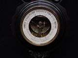 a black and gold barometer on a black wall