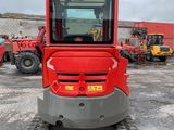 a close up of a small red tractor parked in a parking lot