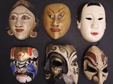 Plusieurs masques de différentes couleurs sont alignés sur une surface noire