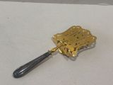 a silver spoon with a gold handle hanging on a wall