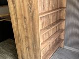 a tall wooden bookcase with shelves in the corner of the room