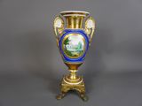 un vase bleu et doré sur lequel est représenté un château