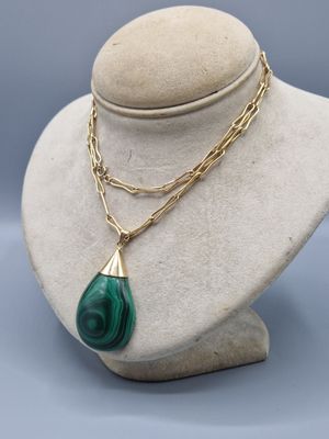un collier vert et or avec un pendentif en forme de larme sur un mannequin