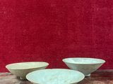 trois bols blancs posés sur une table en bois, près d'un mur rouge