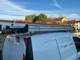 une camionnette avec une échelle sur le toit, garée sur un parking