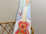 a cardboard guitar sitting on a wicker chair in a room