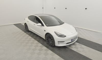 La Tesla Model 3 blanche est garée dans une pièce dont le sol est à carreaux.