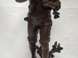 statue en bronze représentant un garçon coiffé d'un chapeau et tenant un oiseau