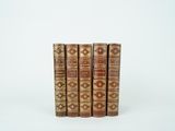 trois vieux livres sont empilés sur une surface blanche