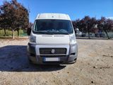the white van is parked on the dirt in the parking lot