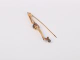 a close up of a pair of gold ear pins on a white surface