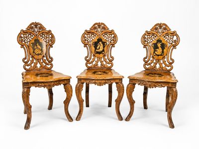 trois chaises en bois ornées de sculptures, disposées les unes à côté des autres