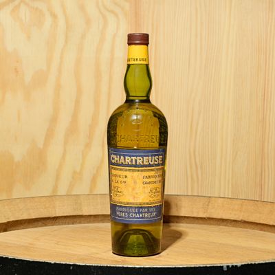 a bottle of whisky sitting on top of a wooden barrel