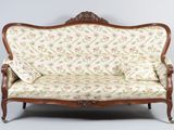 an old fashioned couch with a floral upholstered back and arms