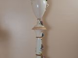 a white vase with flowers on top of it on a table
