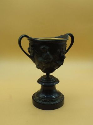 un vase noir orné d'un visage, posé sur une table