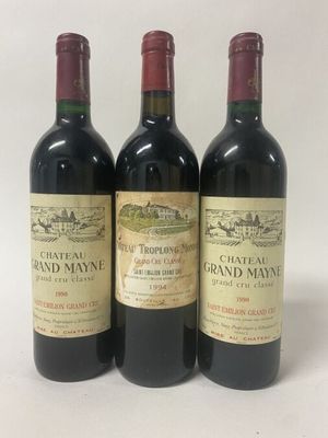 three bottles of red wine sitting on top of a white table