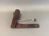 a glass bottle and a leather case on a table