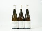 trois bouteilles de vin posées les unes à côté des autres sur une surface blanche