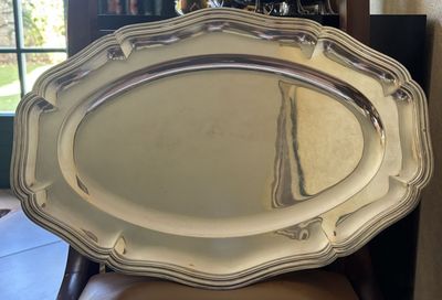 a silver tray sitting on top of a chair in front of a window