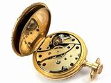a gold pocket watch that is open on a white surface