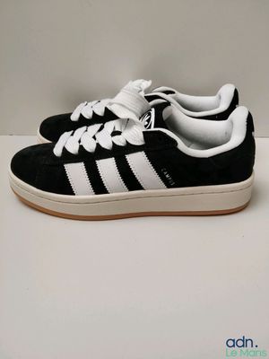 une paire de baskets noires et blanches posées sur une surface blanche