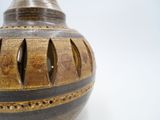 a brown vase with holes in it on a white surface