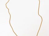a gold necklace with a long chain on a white surface