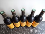 six bottles of wine are lined up on a table