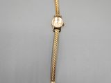 une image représentant une montre en or sur fond gris
