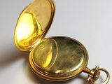 a close up of a gold pocket watch on a white surface