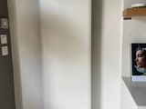 un radiateur dans un coin d'une pièce où est accroché un tableau au mur