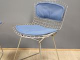 pair of chrome wire chairs with blue cushions against a gray wall